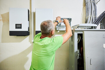 Man electrician installing solar panel system. Inspector making electrical wiring inverter and...