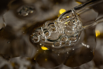 A drop of cosmetic aromatic oil drips from the pipette. Front view.