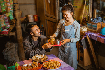 stallholder girl wearing apron serves drinks to customers at a traditional stall