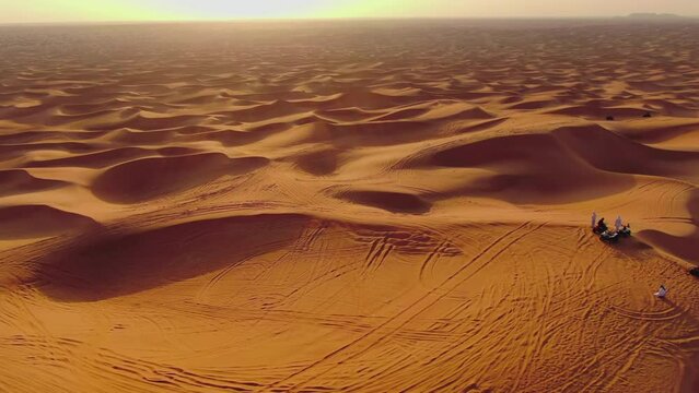 The drone flies to the quadra in cycles standing on sand dunes in the desert of the United Arab Emirates