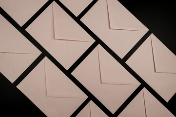 Top view of light pink envelopes on black background. Post flat lay. Copy space.