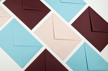 Top view of colourful envelopes on white background. Pink, blue and dark red envelopes flat lay....