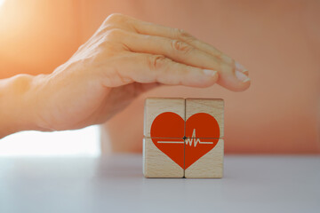 Senior woman place hand over heart icon on wooden cube blocks, for health care and medical, elderly home care, insurance, wellness, well being concept