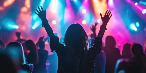 Young woman dancing at a music festival in front of bright stage lights
