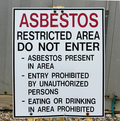 A warning sign at a gas industrial facility with the message: Asbestos restricted area, do not enter.