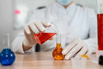 Woman caucasian laboratory assistant  pouring sample into flask in laboratory
