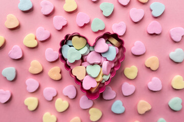 flat lay of a pile of candy hearts against a pink background