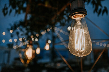 bare lightbulbs glowing at twilight at a wedding reception