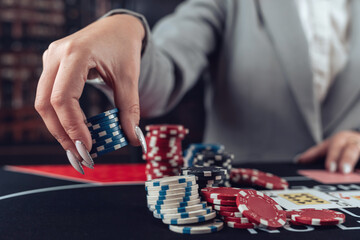 female player plays poker and takes chips to raise the bet