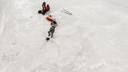 People with ice hole for fishing in frozen lake in winter