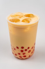 Closeup of a cup of delicious cold yellow bubble tea with red boba