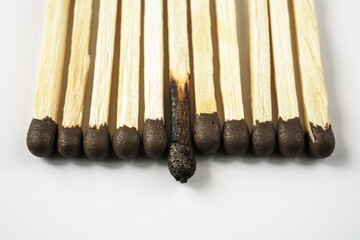 Whole and burnt matches lined up in a row on a white background. The concept of emotional burnout...