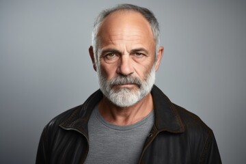Portrait of a serious senior man in a leather jacket over grey background.