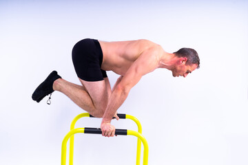 Male gymnast performing handstand on parallel bars, studio shot