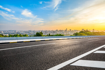 Asphalt road and city skyline with modern buildings scenery at sunrise