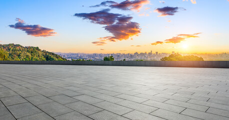 Empty square floor and green mountain with city skyline at sunrise