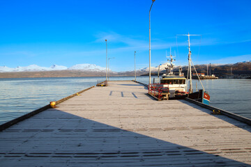 small harbor with a fishing boat in Norway with mountains in the background