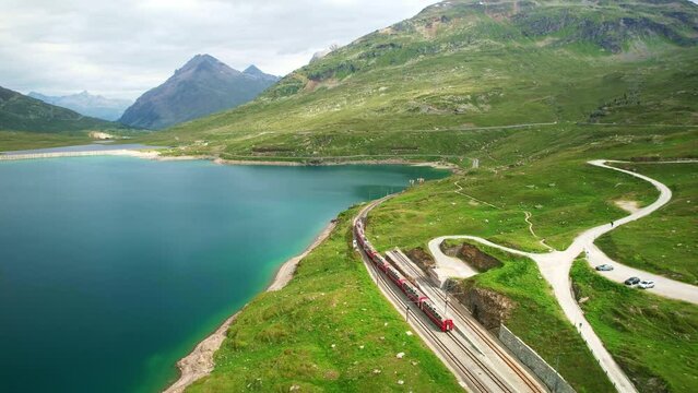 Bernina Express red swiss train in Swiss Alps. Rhaetian Railway famous Lake Bianco on way to St. Moritz. Switzerland summer tourism.
