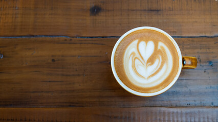 Latte in white and brown cup on wooden table, with latte art