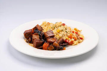 Dinner. Fried eggplant slices in sauce with rice and vegetables on a white plate and a white background