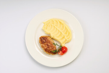 Dinner. Fried cutlet in mashed potatoes on a white plate and a white background
