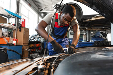Young African male mechanic repairs car in garage close up