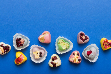 chocolate sweets in the form of a heart with fruits and nuts on a colored background. top view with space for text, holiday concept