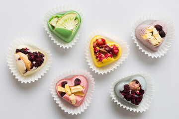 chocolate sweets in the form of a heart with fruits and nuts on a colored background. top view with space for text, holiday concept