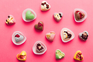 chocolate sweets in the form of a heart with fruits and nuts on a colored background. top view with space for text, holiday concept