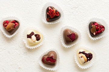 chocolate sweets in the form of a heart with fruits and nuts on a colored background. top view with space for text, holiday concept