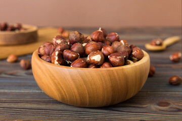 Wooden bowl full of hazelnuts on table background. Healthy eating concept. Super foods