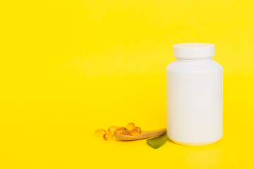 Omega-3 capsules lie in white bottle on a table with green leaves background. Fish oil tablets. Biologically active additives. omega 6, omega 9, vitamin A, E, D, vitamin D3 top view with copy space