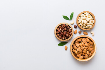 Assortment of nuts in wooden bowl on colored table. Cashew, hazelnuts, walnuts, almonds. Mix of nuts Top view with copy space