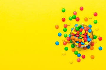 Multicolored candies in a bowl on a colored background. birthday and holiday concept. Top view with copy space
