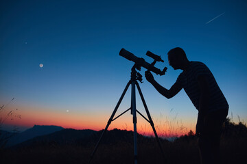 Astronomer looking at the starry skies and crescent Moon with a telescope.