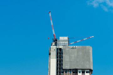 Crane and building construction site against blue sky.
