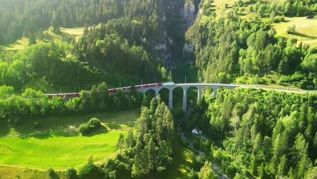famous Glacier Express red swiss train on Landwasser viaduct bridge in Swiss Alps. Rhaetian Railway route Zermatt to St. Moritz. Matterhorn Gotthard Bahn scenic railway. Switzerland summer tourism.