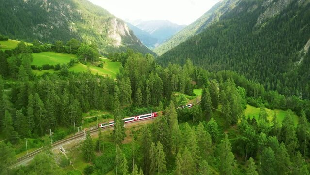 Aerial drone Switzerland. Glacier Express red swiss train in Swiss Alps. Rhaetian Railway scenic route Zermatt to St. Moritz. Viaduct bridge. Switzerland summer tourism.