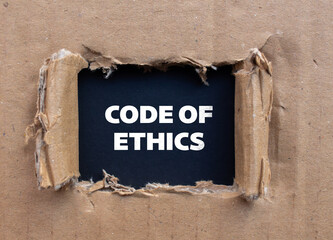 Code of ethics lettering on ripped cardboard paper with black background. Conceptual business...