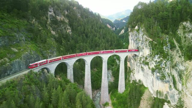 famous Glacier Express red swiss train on Landwasser viaduct bridge in Swiss Alps. Rhaetian Railway route Zermatt to St. Moritz. Matterhorn Gotthard Bahn scenic railway. Switzerland summer tourism.