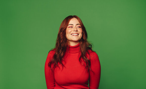 Happy woman standing on green background with trendy style.