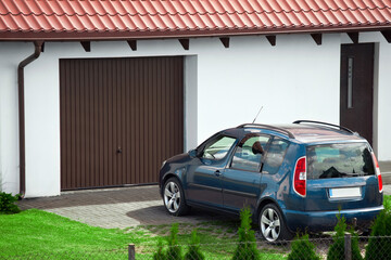 Fototapeta premium blue family car parked near garage of the detached house