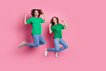 Full body length photo of two teenagers wear green t shirt jumping crazy victory school team...