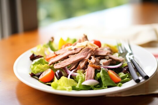 sliced gyro meat atop a greek salad with a fork