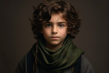 Cute little boy with curly hair and green scarf. Studio shot.