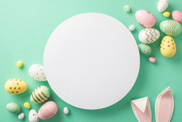 Sweet Easter greetings! Top view of colorful eggs, and funny bunny ears on a turquoise surface. Blank circle perfect for text or adverts - obrazy, fototapety, plakaty