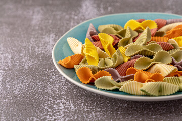 Colorful pasta background. Top view of five colors pasta shells .Heap of colorful spiral...