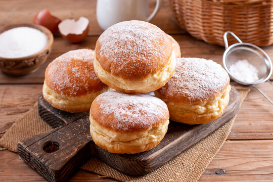 Hanukkah sweet food doughnuts sufganiyot with powdered sugar and fruit jam on a wooden board. Jewish holiday Hanukkah concept.