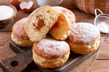 Hanukkah sweet food doughnuts sufganiyot with powdered sugar and fruit jam on a wooden board....