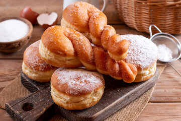 Fresh homemade donut sprinkled with powdered sugar on a board